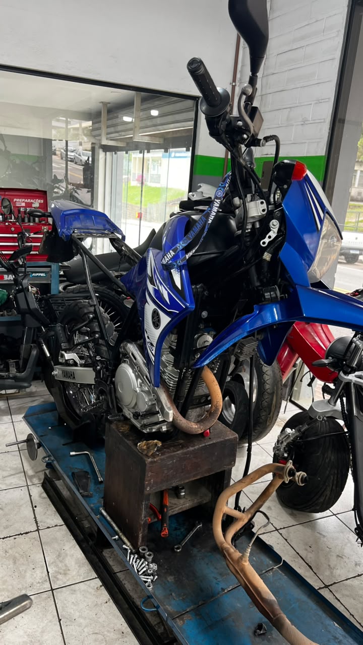 Yamaha XTZ em manutenção com peças no elevador